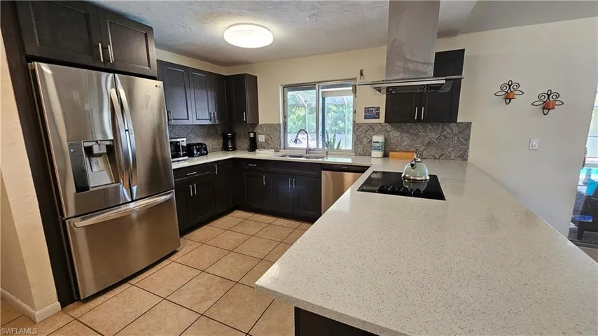 Kitchen featuring tasteful backsplash, island exhaust hood, stainless steel appliances, and sink