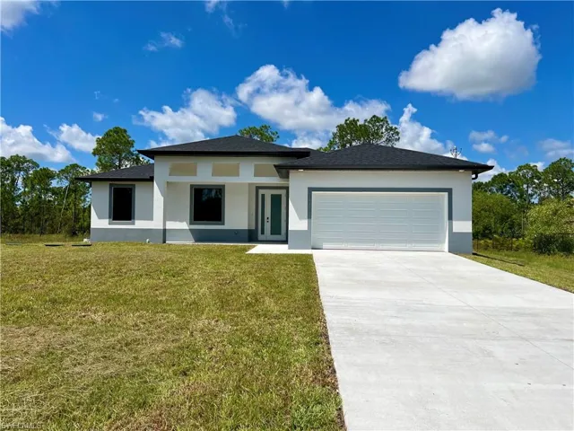 View of front facade featuring a front yard and a garage