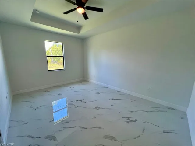 Primary bedroom featuring ceiling fan and a tray ceiling