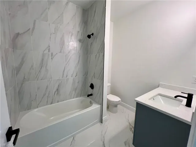 Full bathroom featuring tiled shower / bath, vanity, and toilet