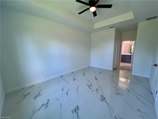 Primary bedroom featuring ceiling fan and a tray ceiling