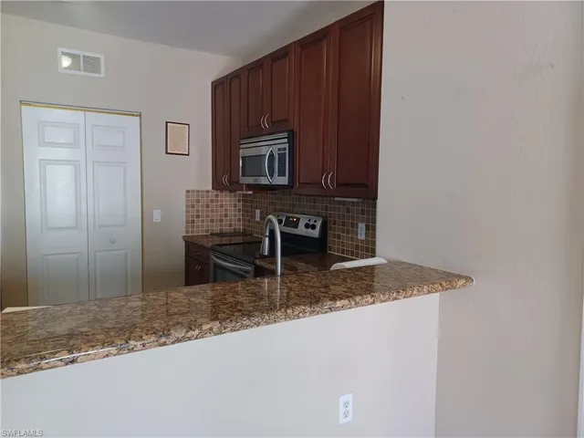Kitchen with backsplash, appliances with stainless steel finishes, and dark brown cabinetry