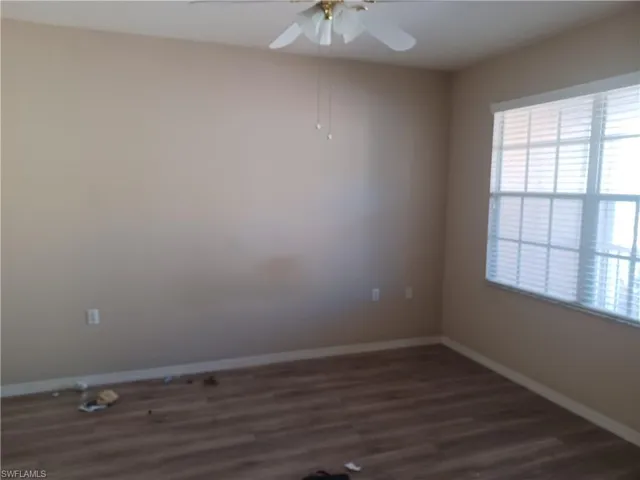 Empty room with dark wood-style floors and a ceiling fan