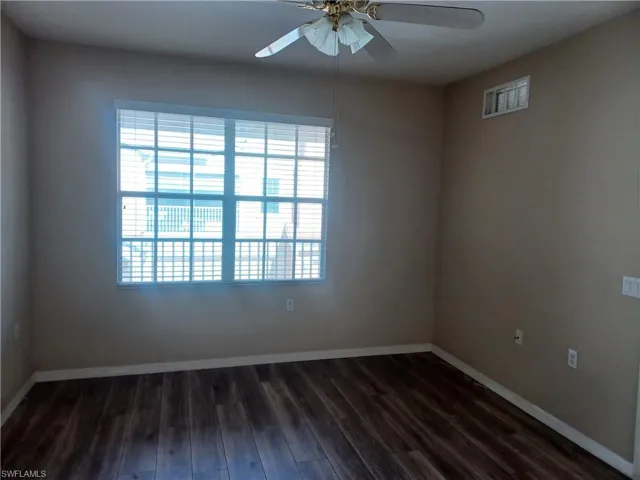 Empty room with dark wood-style flooring and ceiling fan
