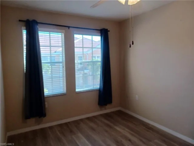Unfurnished room featuring dark wood-type flooring and a ceiling fan