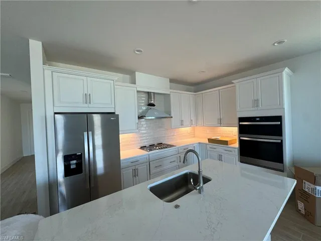 Kitchen layout with stainless steel appliances, gas cooktop, hooded vent, wall oven/wall microwave combo