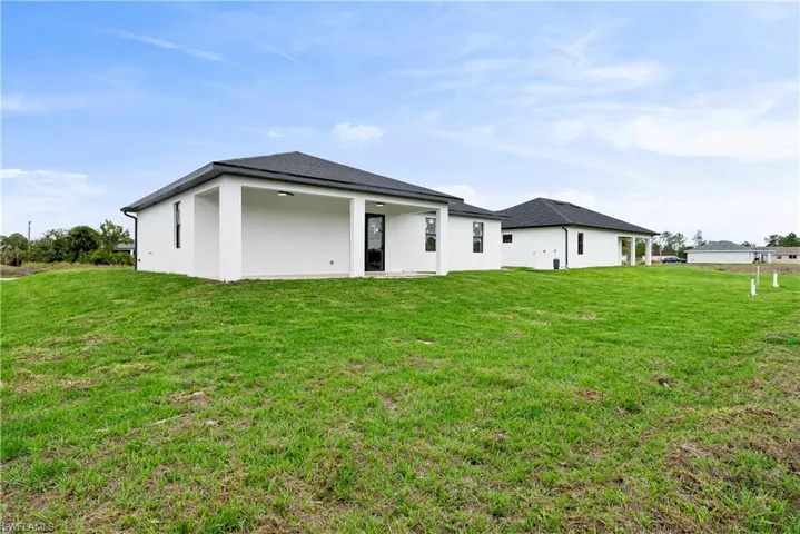Back of house featuring a lawn, a patio, and stucco siding