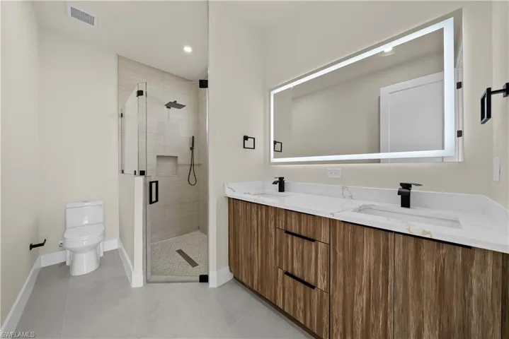 Bathroom with double vanity, a shower stall, recessed lighting, and light tile patterned flooring