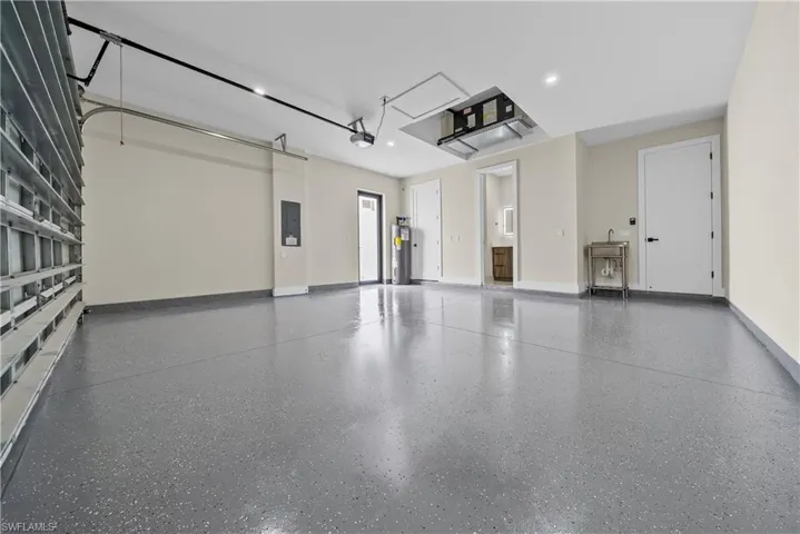 Garage featuring electric panel, water heater, and recessed lighting