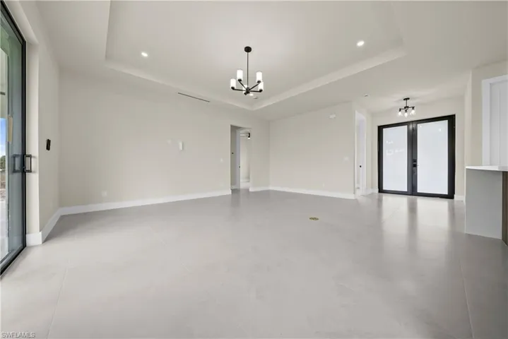Unfurnished room with hanging lights, a raised ceiling, plenty of natural light, and french doors