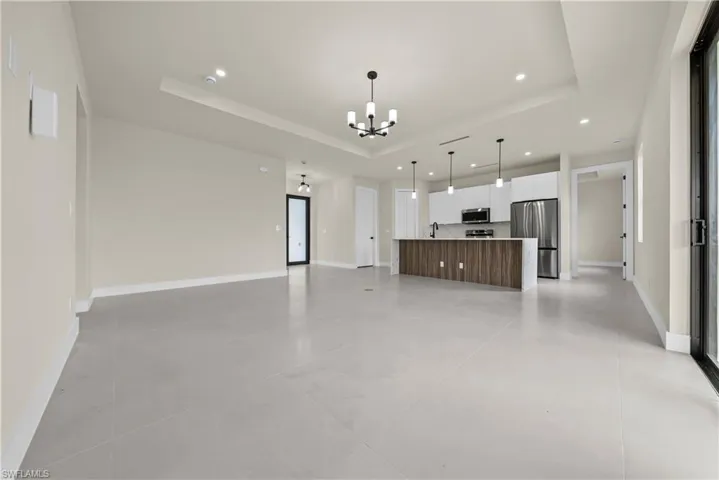 Unfurnished living room with a raised ceiling and suspended lighting