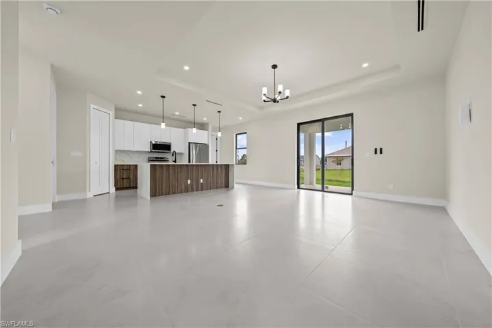 Unfurnished living room with a chandelier and a tray ceiling