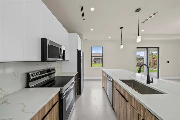 Kitchen with stainless steel appliances, modern cabinets, light stone countertops, dual tone cabinets, and tasteful backsplash