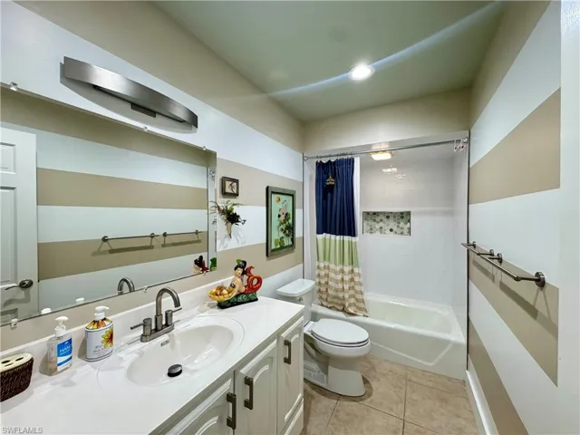 Bathroom with shower / bath combo, vanity, and light tile patterned flooring