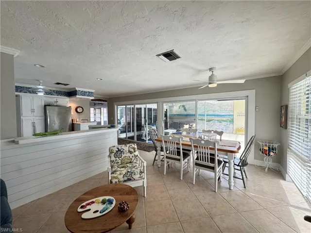 Dining room with light tile patterned floors, crown molding, healthy amount of natural light, and a textured ceiling