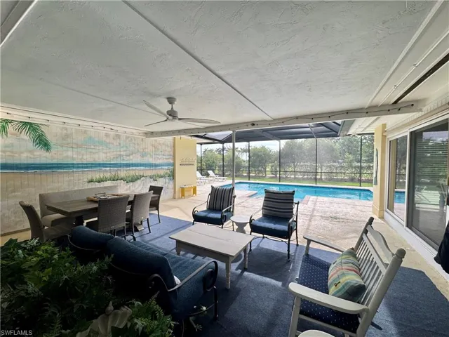 View of patio / terrace with a sunroom, glass enclosure, a ceiling fan, outdoor dining space, and an outdoor pool