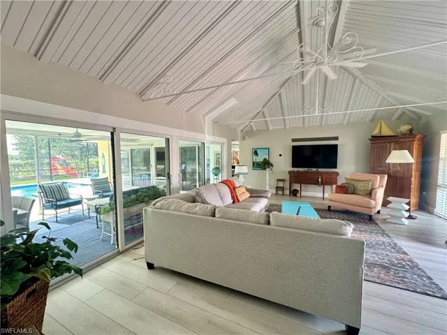 Living room with a ceiling fan, wood finished floors, high vaulted ceiling, and a sunroom