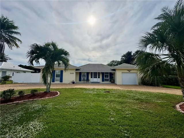 Single story home with dirt driveway, stucco siding, an attached garage, and a tile roof