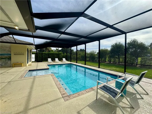 Outdoor pool featuring a sunroom, a lanai, a patio area, and a yard
