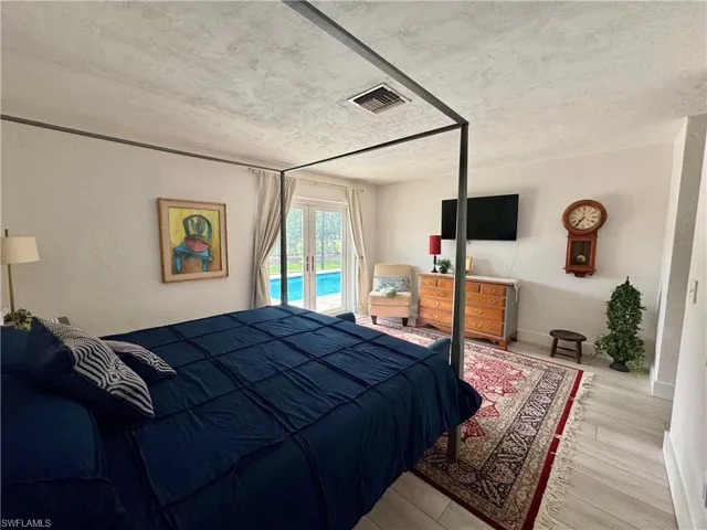 Bedroom with access to outside, wood finished floors, and a textured ceiling