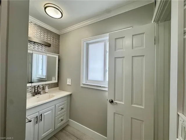 Bathroom featuring vanity, crown molding, and decorative backsplash