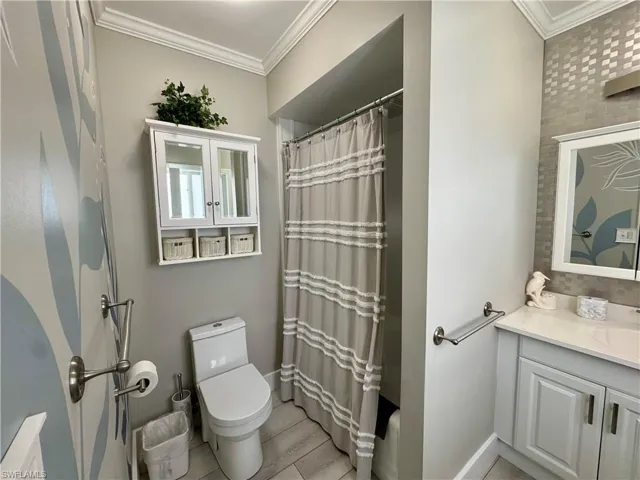 Bathroom featuring curtained shower, ornamental molding, and vanity
