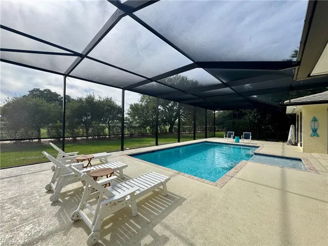 Swimming pool with a patio, glass enclosure, a sunroom, and a lawn
