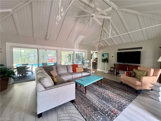 Living room featuring high vaulted ceiling, plenty of natural light, wood finished floors, ceiling fan, and beamed ceiling