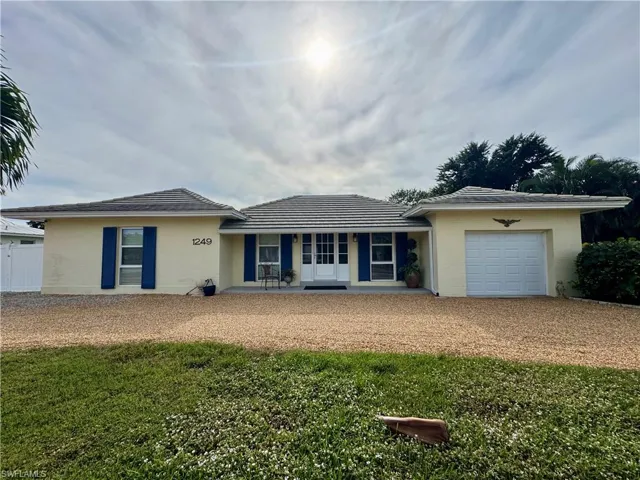 Single story home featuring a garage, driveway, a tiled roof, and a front lawn