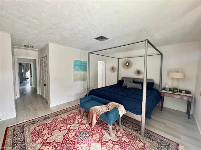 Bedroom featuring a textured ceiling, light wood-type flooring, and a closet
