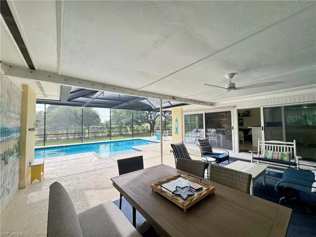 Outdoor pool featuring a patio area, a sunroom, glass enclosure, and outdoor dining space