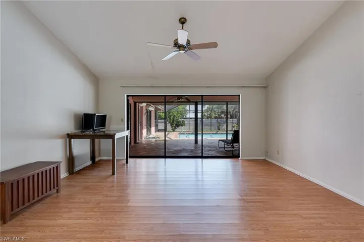 Spare room with a ceiling fan, light wood finished floors, and vaulted ceiling