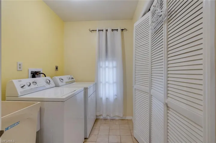 Laundry room with independent washer and dryer and light tile patterned floors
