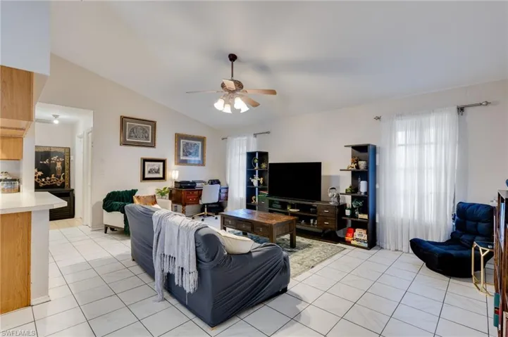 Living room featuring ceiling fan, lofted ceiling, and light tile patterned floors