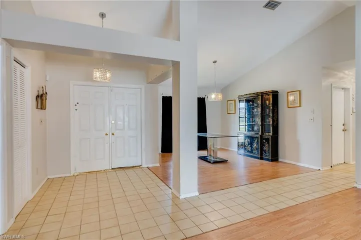 Entrance foyer with light tile patterned flooring, lofted ceiling, and hanging lights