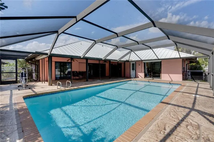 Swimming pool with a sunroom, a patio area, and glass enclosure