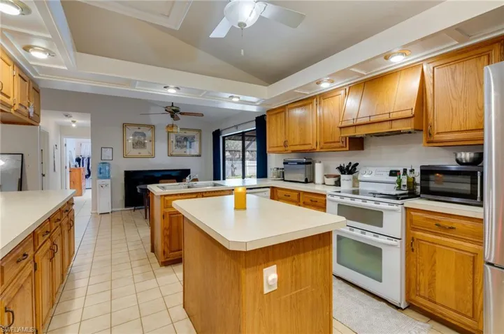 Kitchen featuring lofted ceiling, double oven range, wood finish cabinets, a peninsula, and light countertops