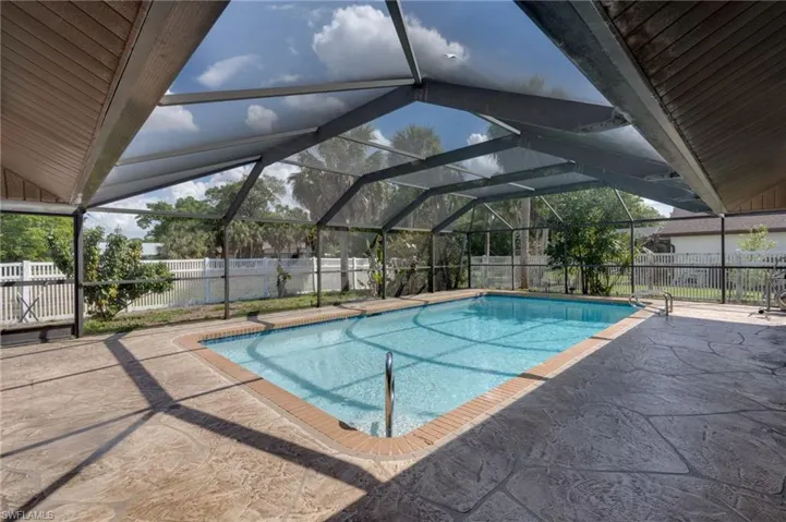 View of pool with a fenced backyard, patio surround, glass enclosure, and a sunroom