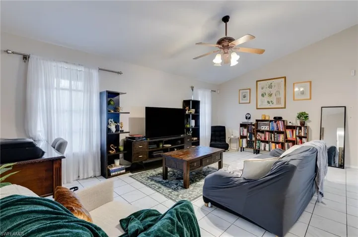 Living room featuring light tile patterned floors, a ceiling fan, and lofted ceiling