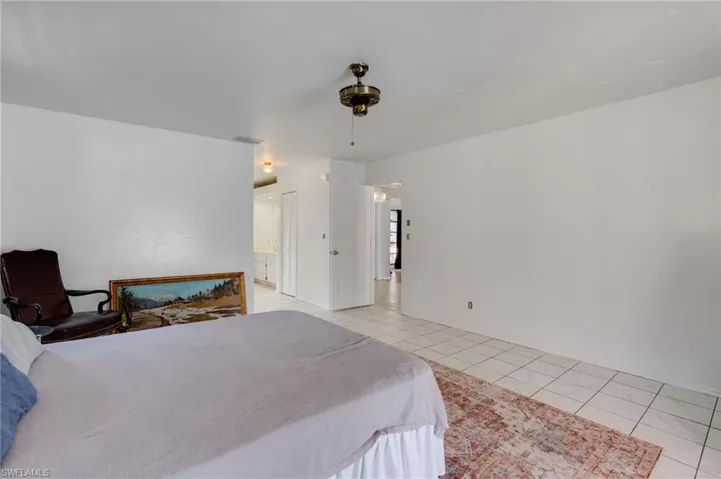 Bedroom with a closet, connected bathroom, a ceiling fan, and light tile patterned floors