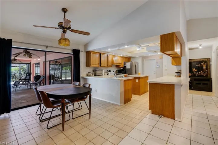 Kitchen with a peninsula, wood finish cabinets, a ceiling fan, light countertops, and lofted ceiling