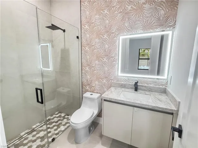 Modern bathroom featuring a frameless glass shower enclosure with a rain shower head