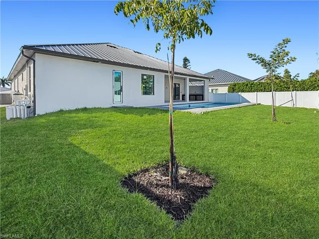 Rear view of house with a patio, stucco siding, a fenced backyard, and a metal roof