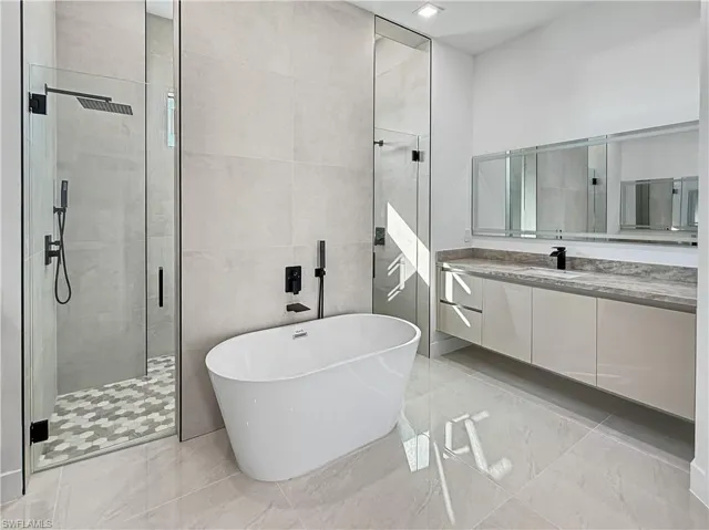 Full bathroom with a freestanding bath, vanity, a shower stall, and tile walls