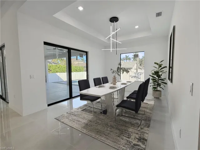 Dining room with a tray ceiling, healthy amount of natural light, recessed lighting, and light tile patterned flooring
