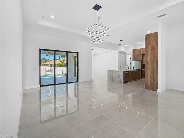 Unfurnished living room featuring recessed lighting, a chandelier, and a tray ceiling