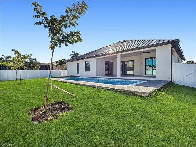 Back of house with a ceiling fan, a fenced backyard, a patio, stucco siding, and a metal roof