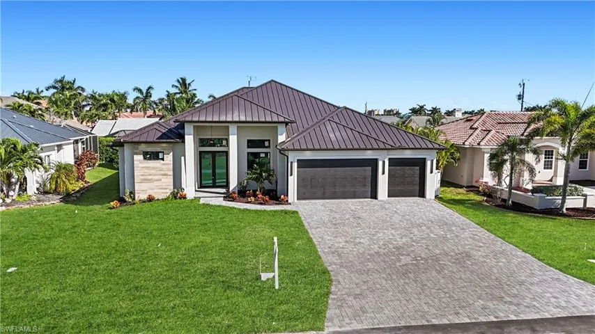View of front facade featuring a metal roof, a front lawn, a standing seam roof, decorative driveway, and an attached garage
