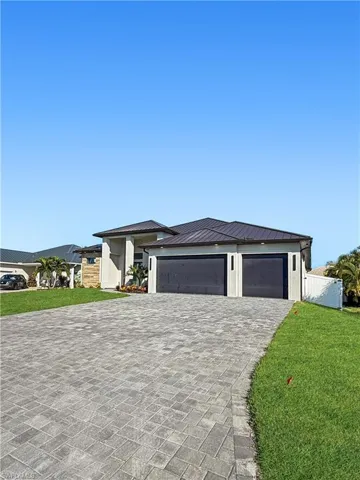 Prairie-style house with a front yard, decorative driveway, an attached garage, and a metal roof