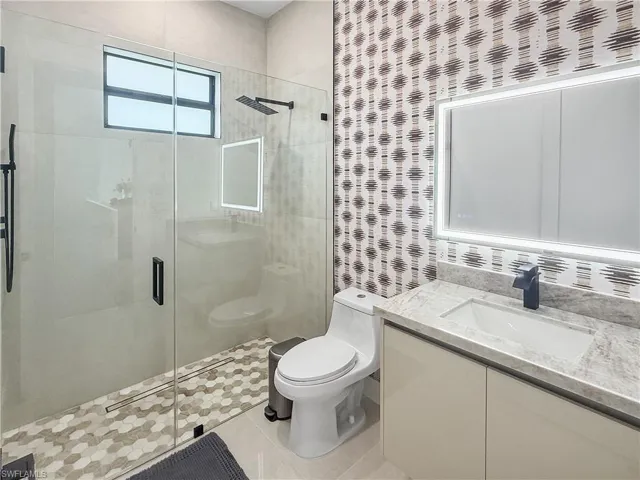 Bathroom featuring a glass-enclosed shower with a mosaic tile floor, matte black shower fixtures, and a transom window